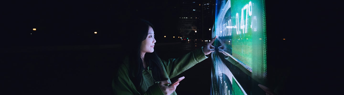 Une femme souhaitant passer du plein air la nuit interagit avec un écran numérique