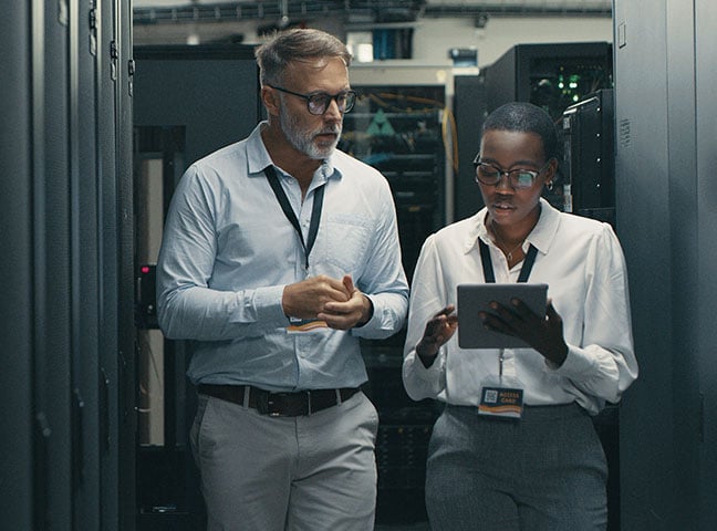 A man and woman using a digital tablet while working in a data centre